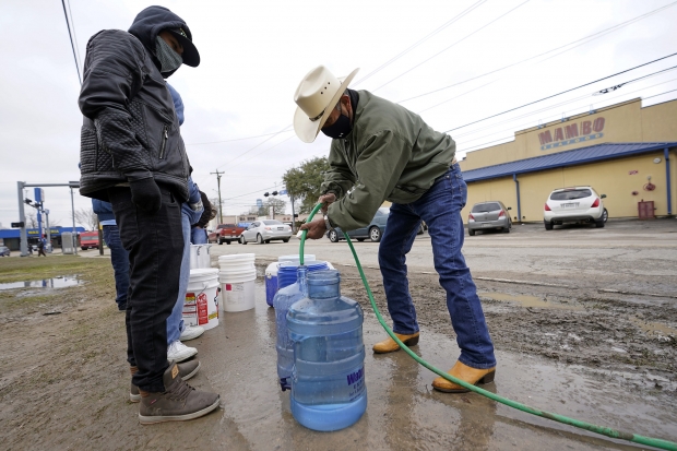 Leovardo Perez, right, fills a water jug using a hose from a public park water spigot Thursday, Feb. 18, 2021, in Houston. Houston and several surrounding cities are under a boil water notice as many residents are still without running water in their homes. David J. Phillip/AP Photo