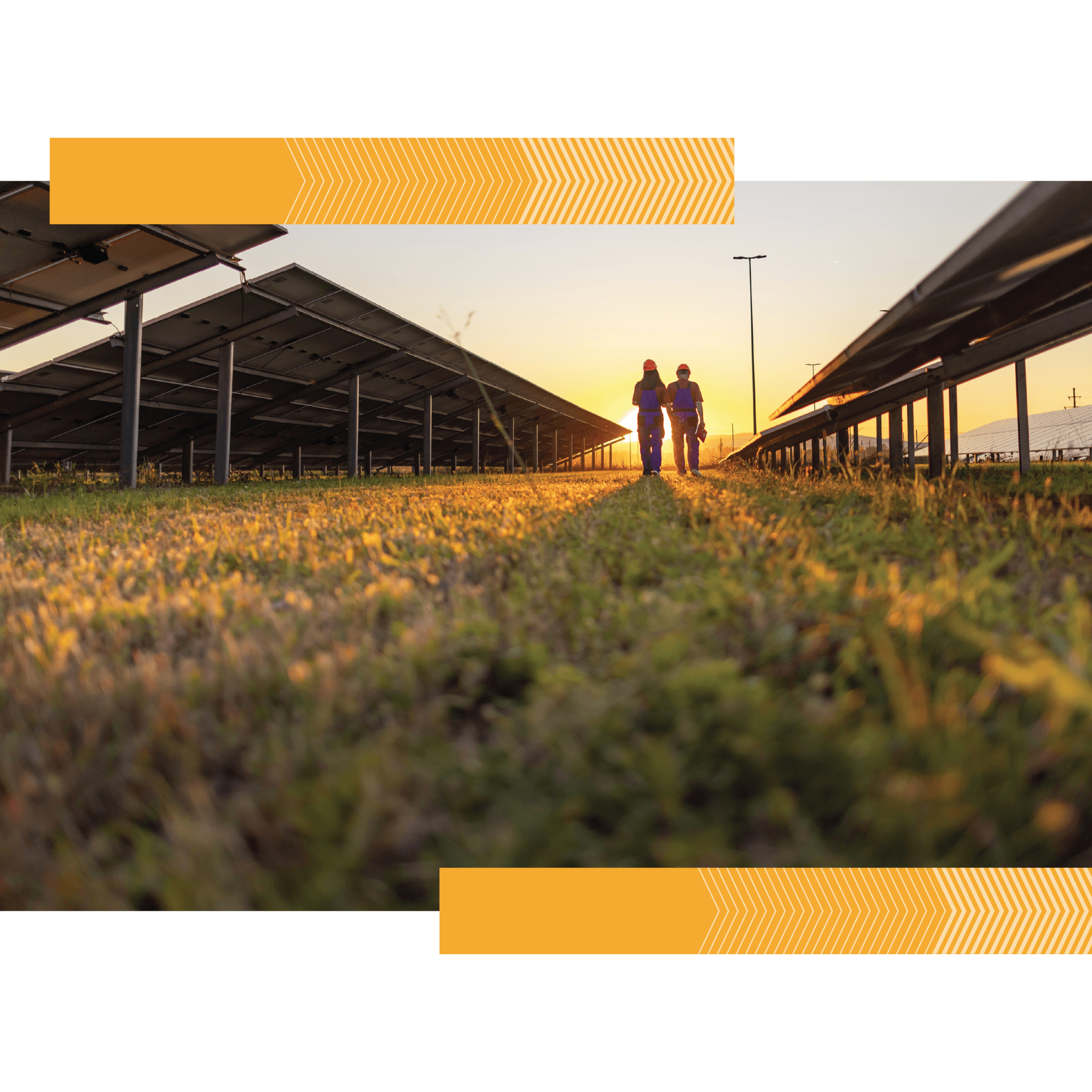 Two solar technicians walk through a solar farm toward a rising sun
