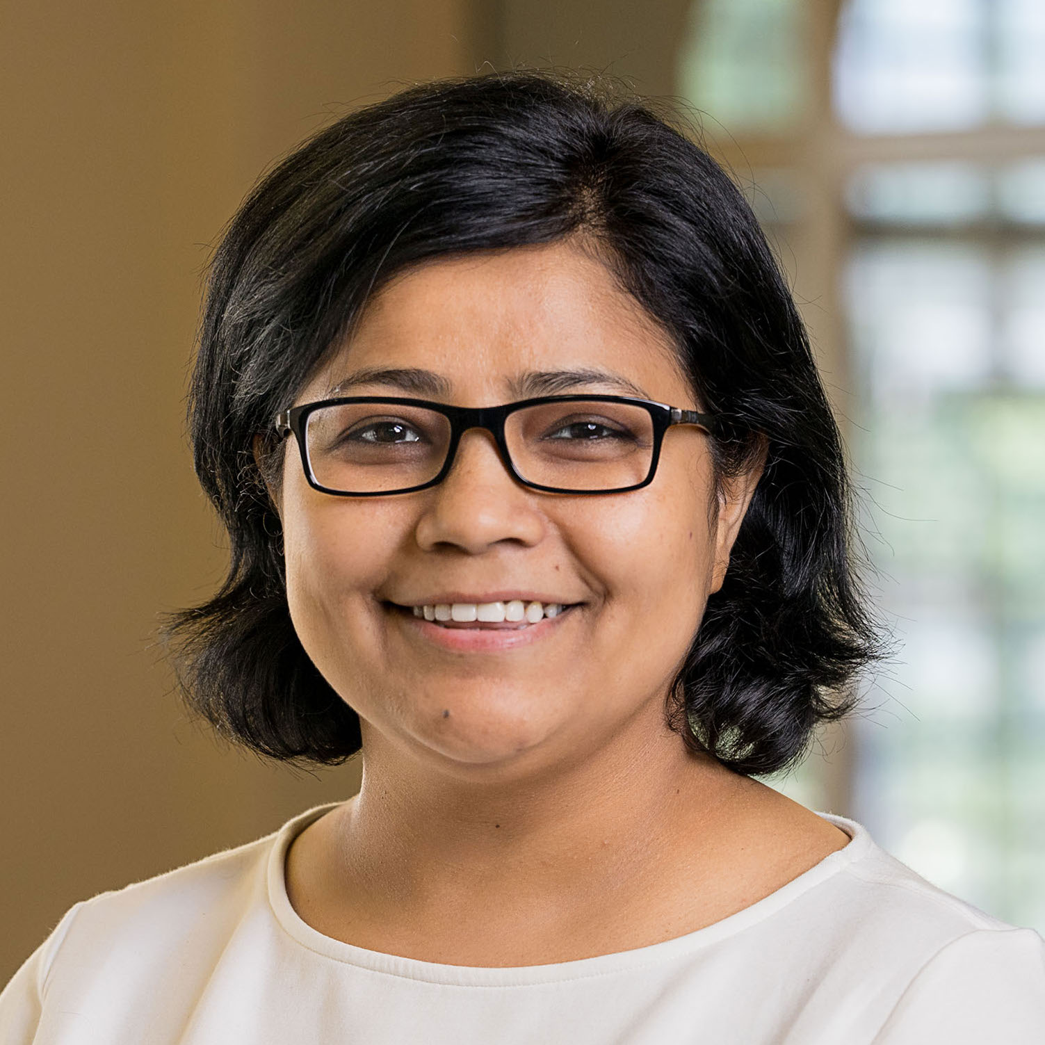 Headshot of a woman with light brown skin, short black hair, and glasses
