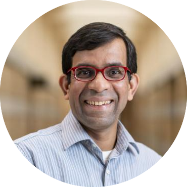 headshot of a south asian man with short black hair and glasses