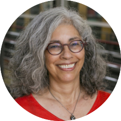 headshot of a medium skinned woman with long curly gray hair and glasses